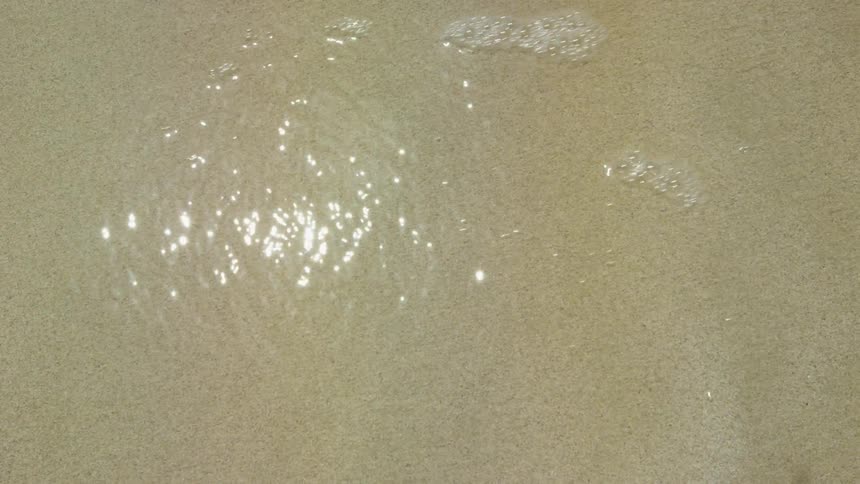 Ocean waves flow over a sandy beach