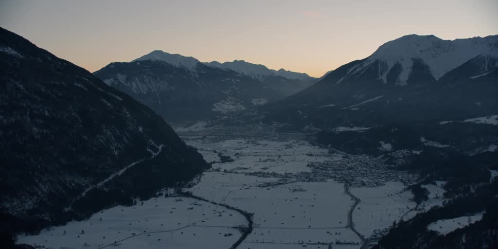 The sun sets over snowy mountains
