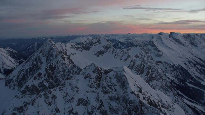 Snow covered mountains under a cloudy blue sky