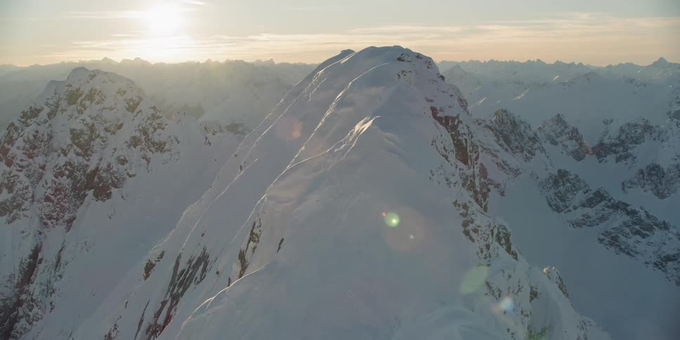 The sun sets over snowy mountains
