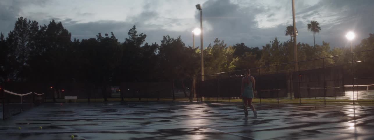 Woman carries a tennis racket as she walks on the court