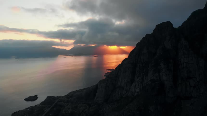 The setting sun shines through clouds over the ocean