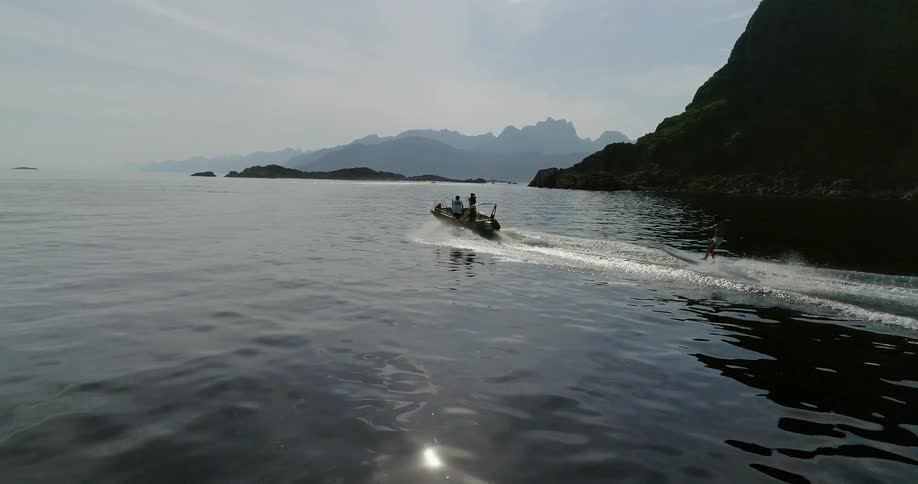 A person riding water skis behind a boat as it sails down a large body of water