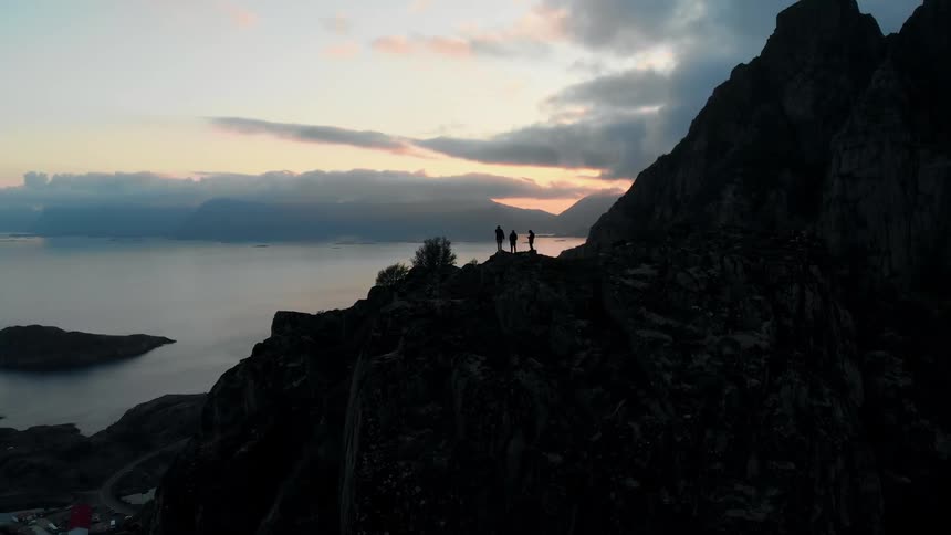 Hikers stand on a mountain peak at sunset