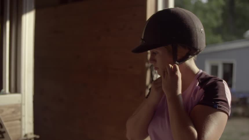 A young woman putting on a helmet