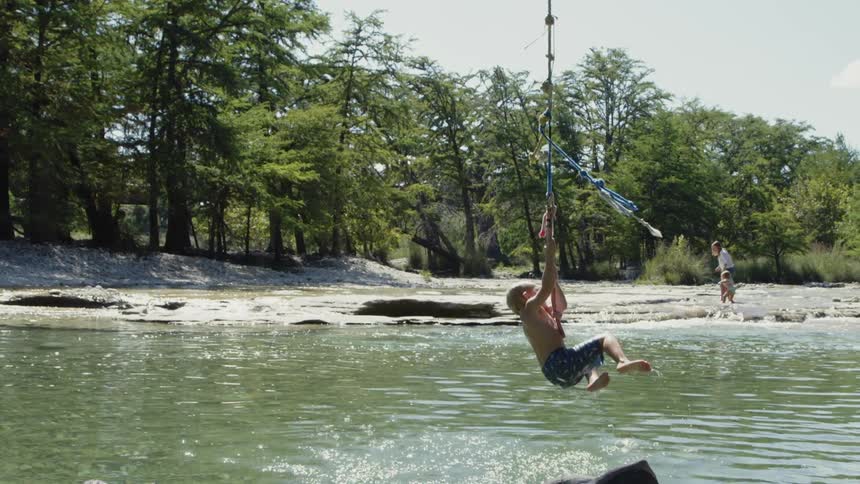 Child swings on a rope into a lake of water