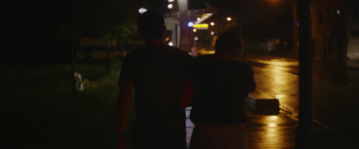 Man and woman walk on a city sidewalk at night