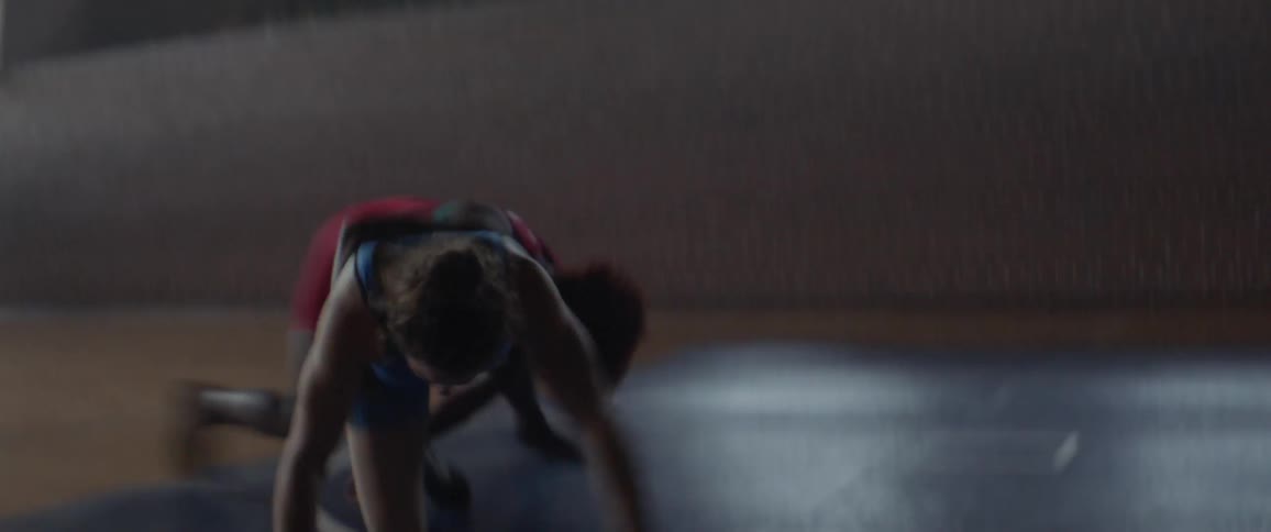 Two women are wrestling on a mat in a gymnasium during the day