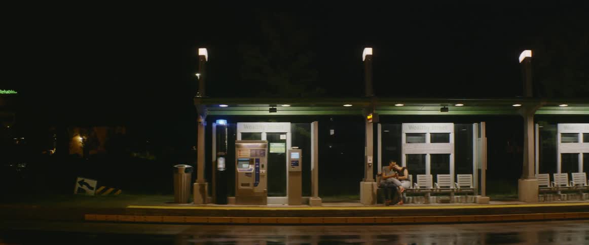 Man and woman sit outside of a building at night