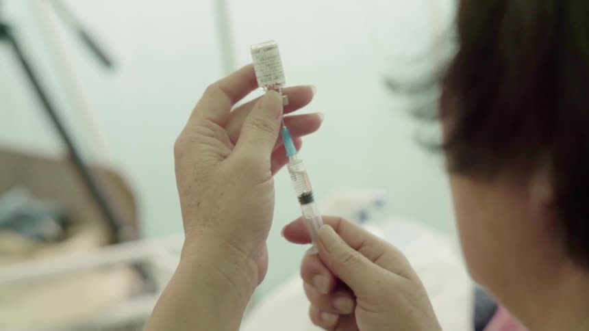 Woman fills a syringe from a small bottle