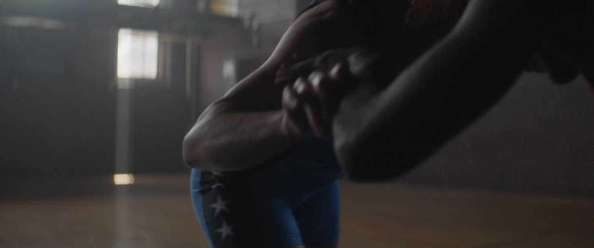 Two women wrestle in a large room