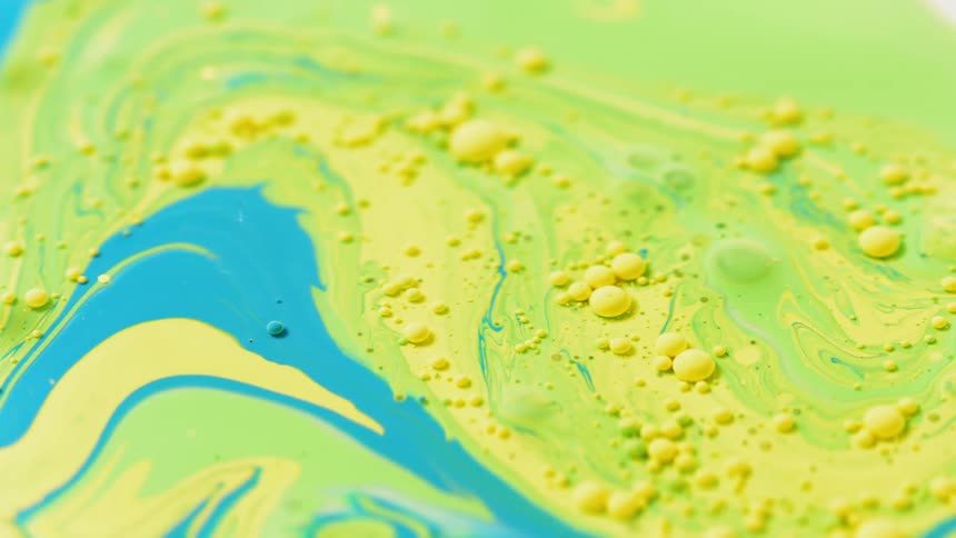 Blue swirls through yellowish and greenish liquid
