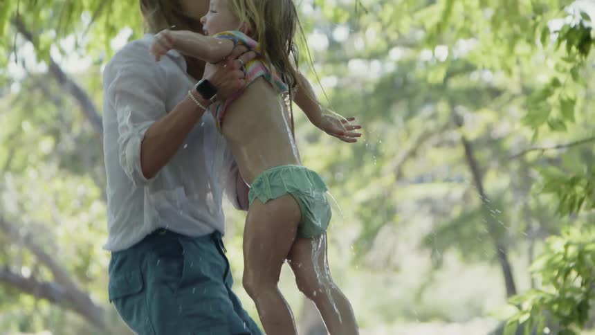A woman lifts a swimming girl from a lake