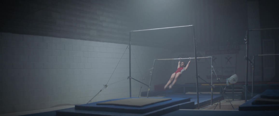 The woman jumps on the bars doing gymnastics