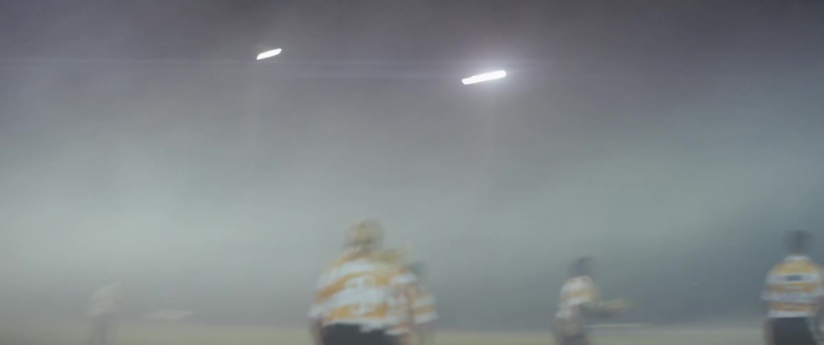 A team of girls play football on a field at night