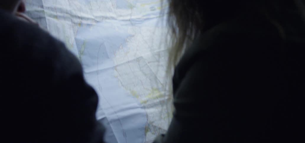 A woman and a man sitting inside a car look at a large map