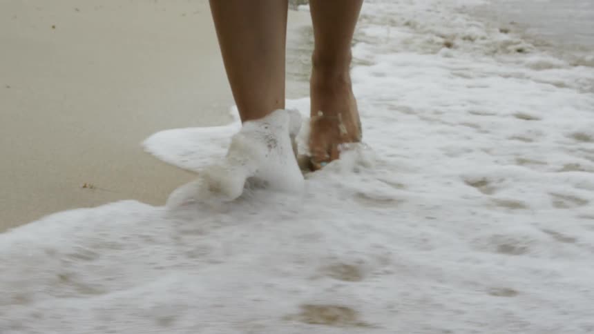 Woman walks barefoot on a sandy beach