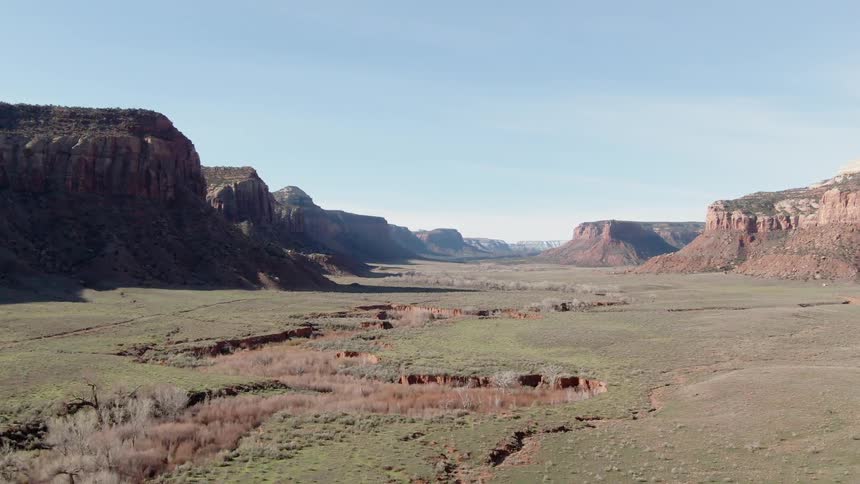 Green grass and flat hills sit under a blue sky