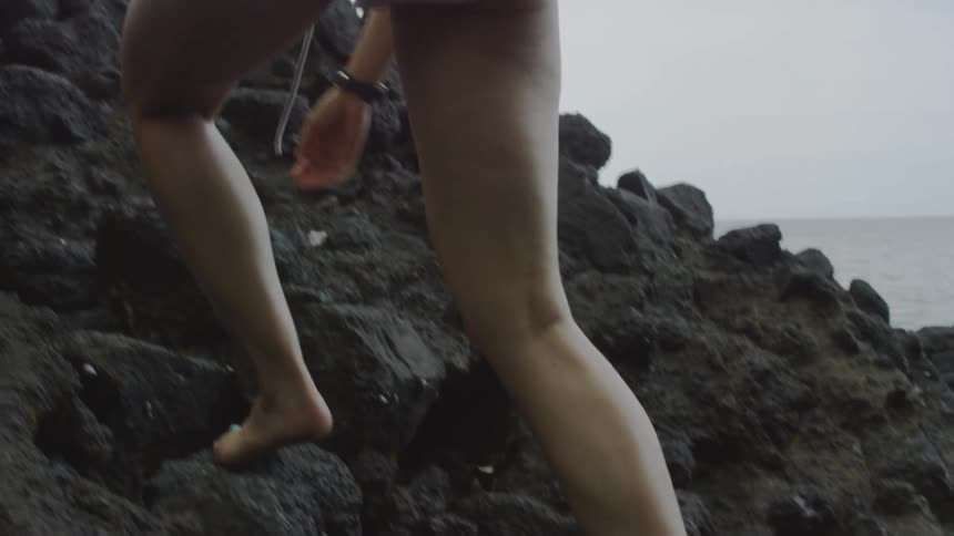 Person steps on a log and up a hill of rocks barefoot