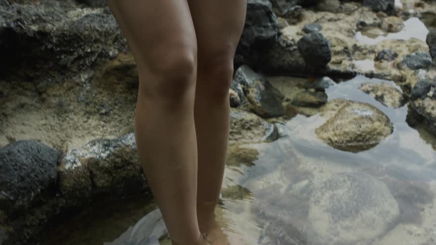 A woman wades in water on a beach