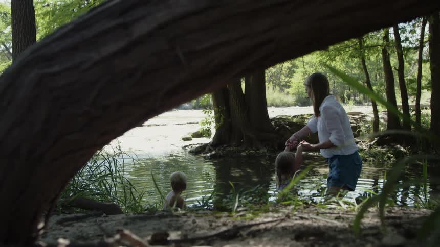 A woman swings a young child into the river water
