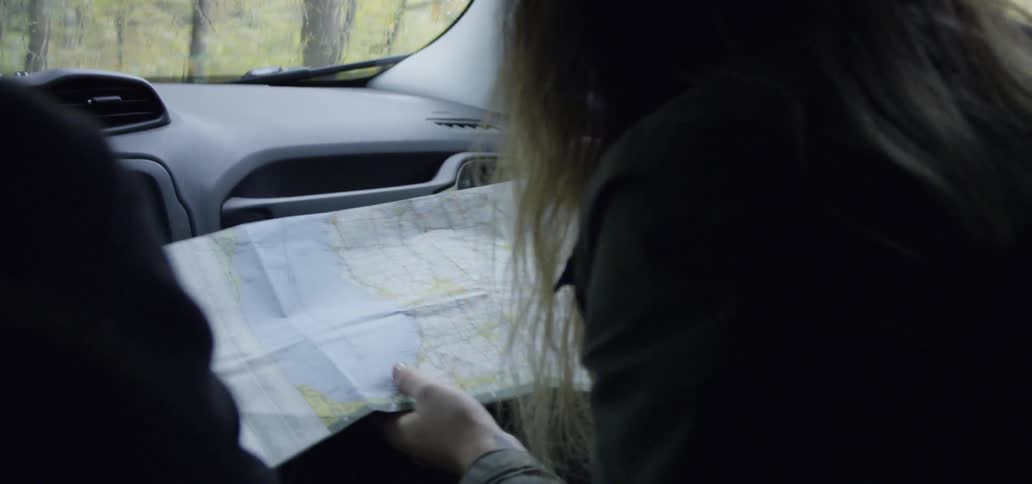 Woman sits in a car looking at a map
