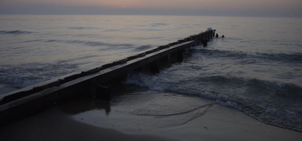 Waves roll in next to the pier