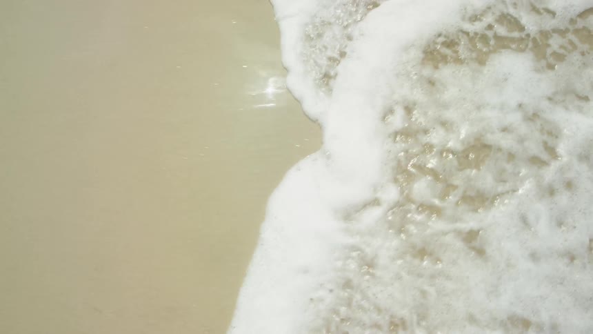 Foamy waves roll into the sandy beach