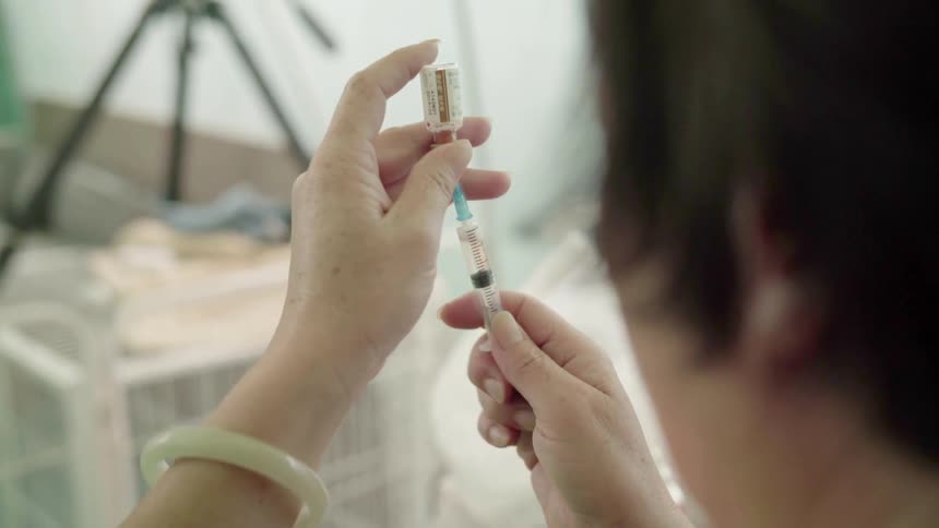 A woman fills a vial preparing to inject it