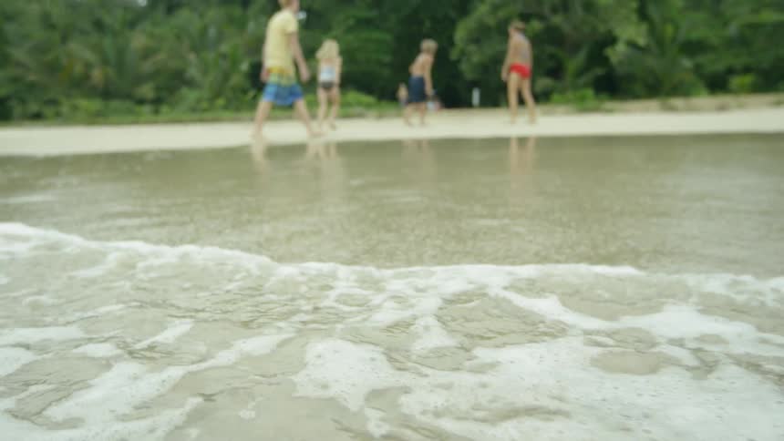 Children and adults walk on the beach near the water