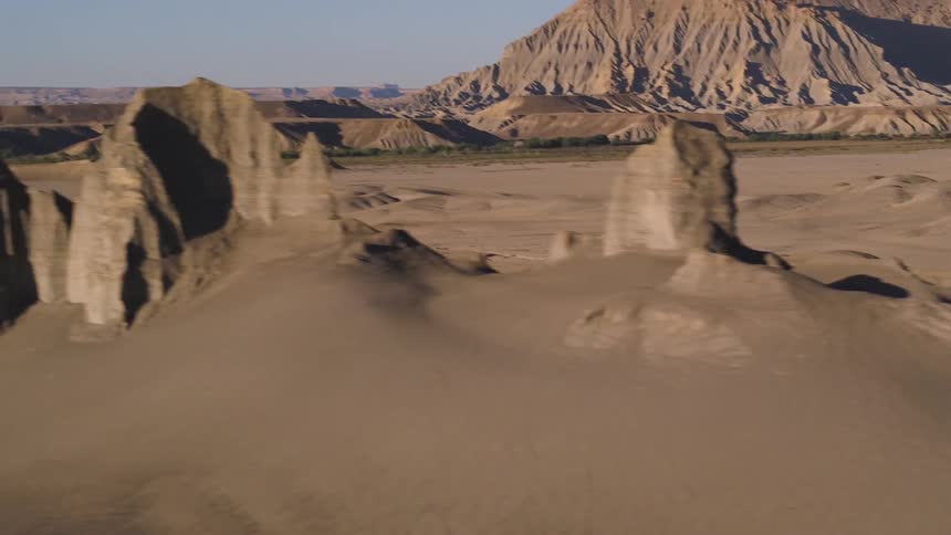 Rock formations and dirt hills stand in a desert