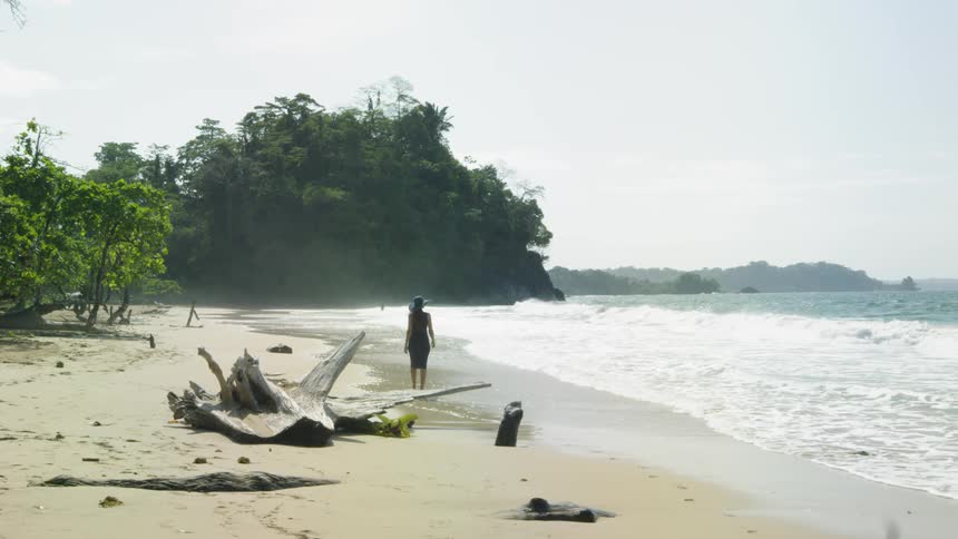 A woman walks on a sandy beach
