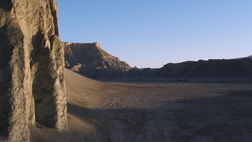 Rock formations stand in a desert at sunset
