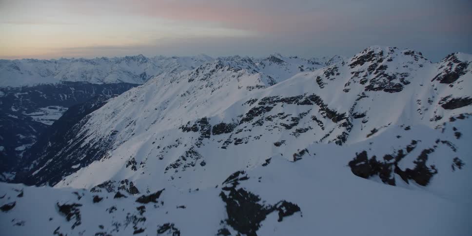 Snow covers mountain peaks at sunset