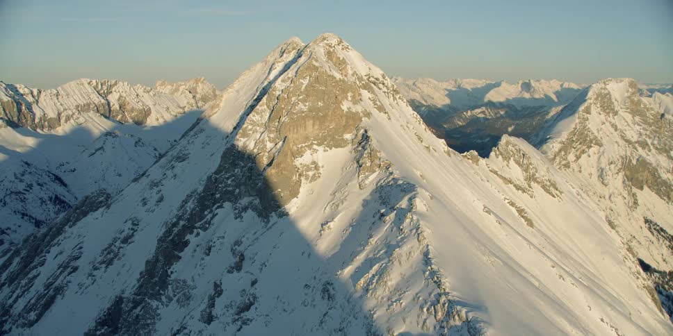Sunlight is casting a glow on a mountain range in winter