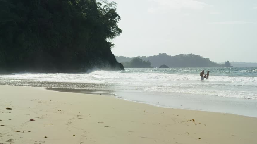 Two people standing in the water near the beach