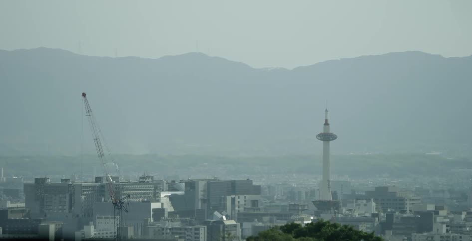 A spire and a crane stand above the rooftops of a city