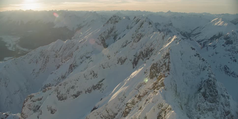 The sun sets over snowy mountains