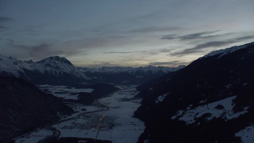 The sun sets over snowy mountains