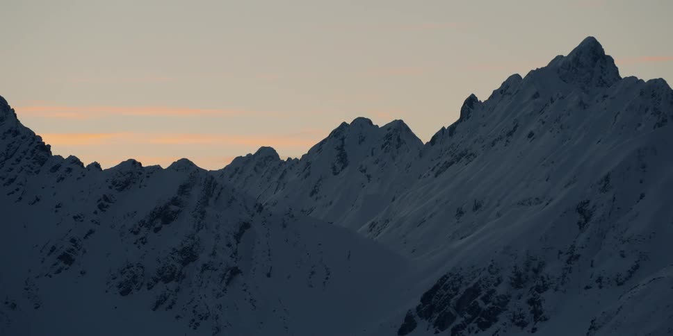 The sun sets behind snowy mountains