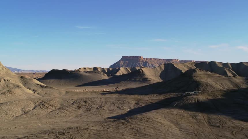 Travelers hike over dirt hills in the wilderness