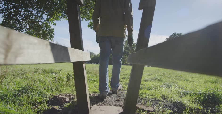 Man walks across a wood bridge in a rural field