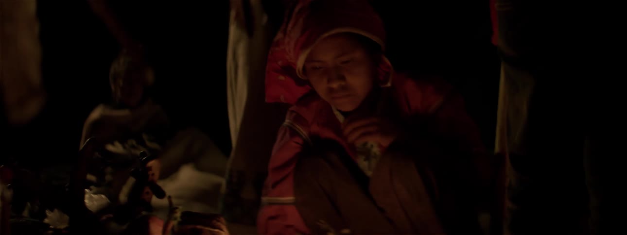 A person crouches down by the fire