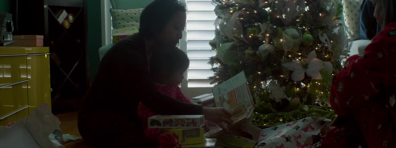 A parent opens christmas presents with a child