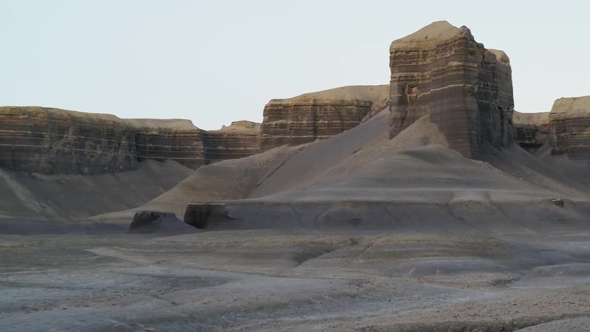 The desert leads to tall rocks in the distance