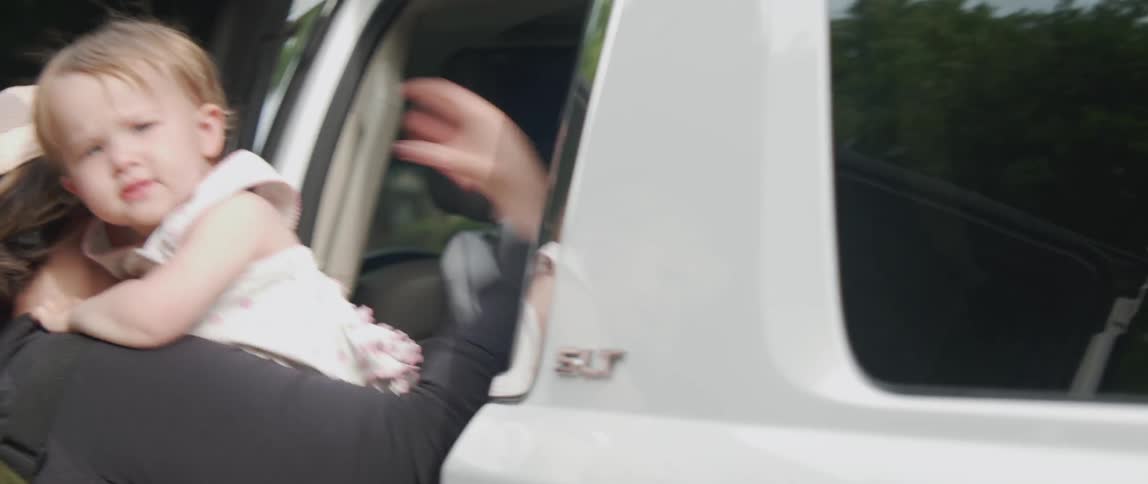 A woman pulls a baby from the vehicle back seat
