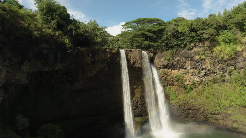 The waterfall is pouring off the side of the cliff