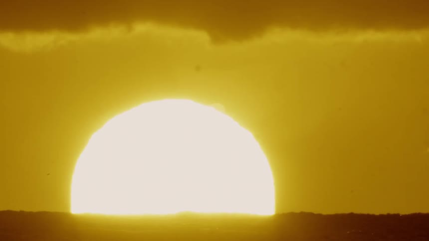 The sun slowly sets into the water