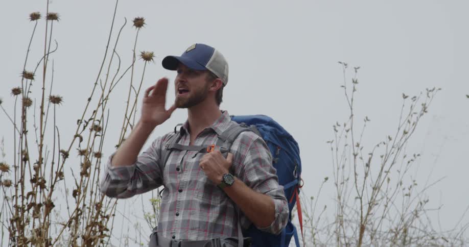 Man with a backpack turns to call out to someone