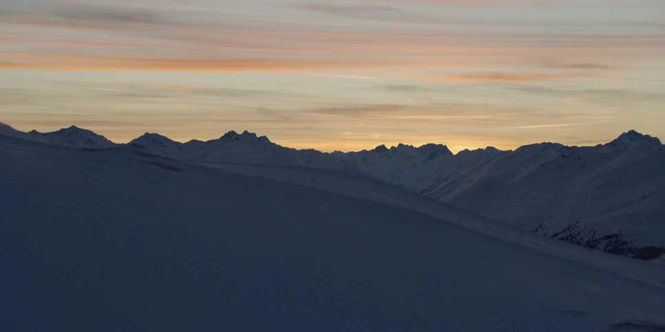 Sun sets over snow covered mountains
